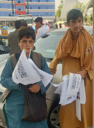 کودکان دستفروش در حال فروش پرچم طالبان